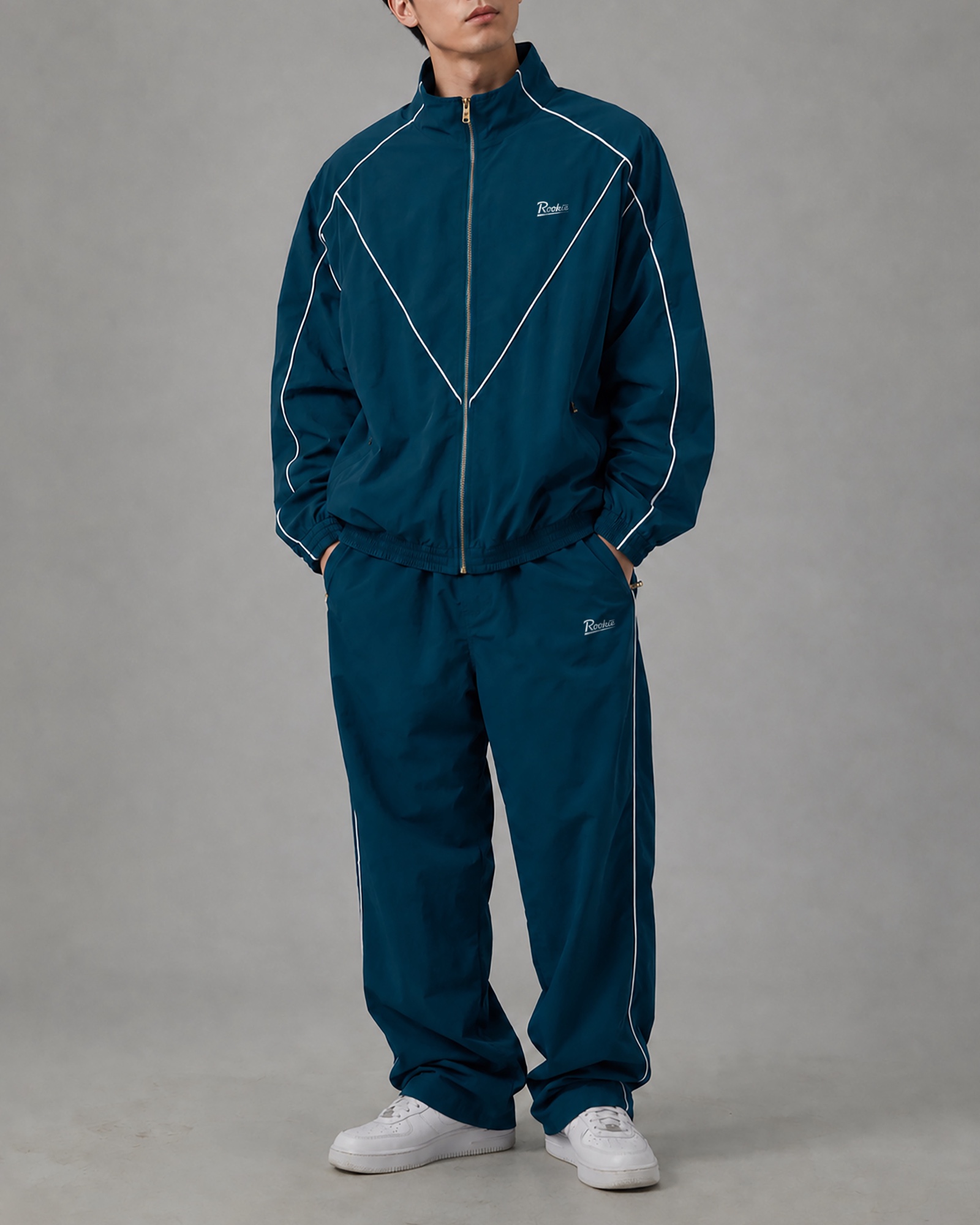 Model in a teal Rookie tracksuit with white piping, framed from the chin down